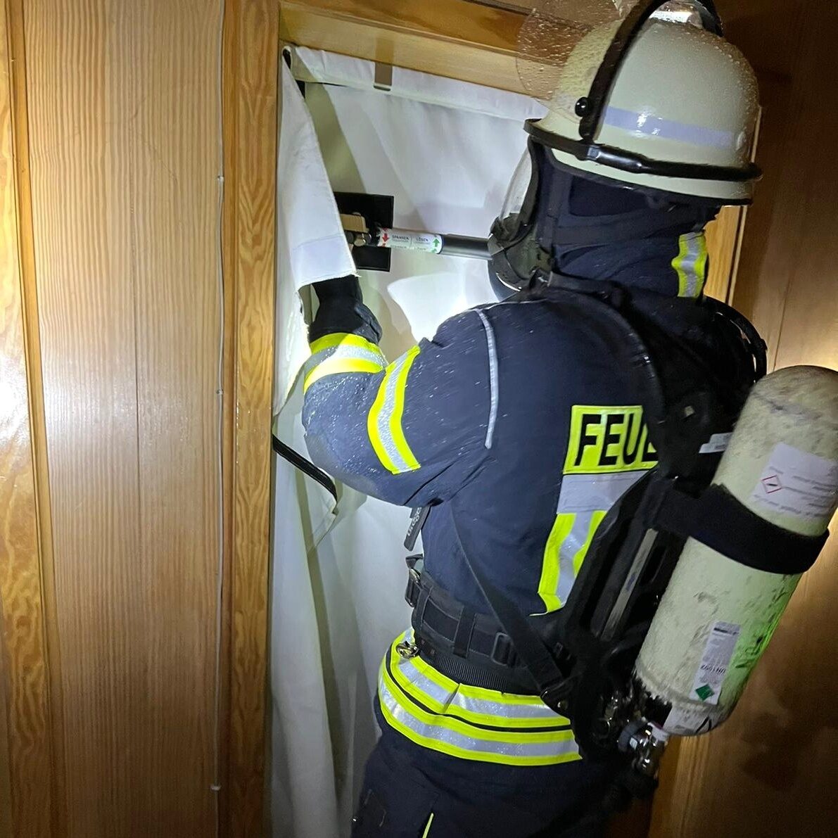 Ein Feuerwehrmann hält ein weißes Tuch in einen Türrahmen