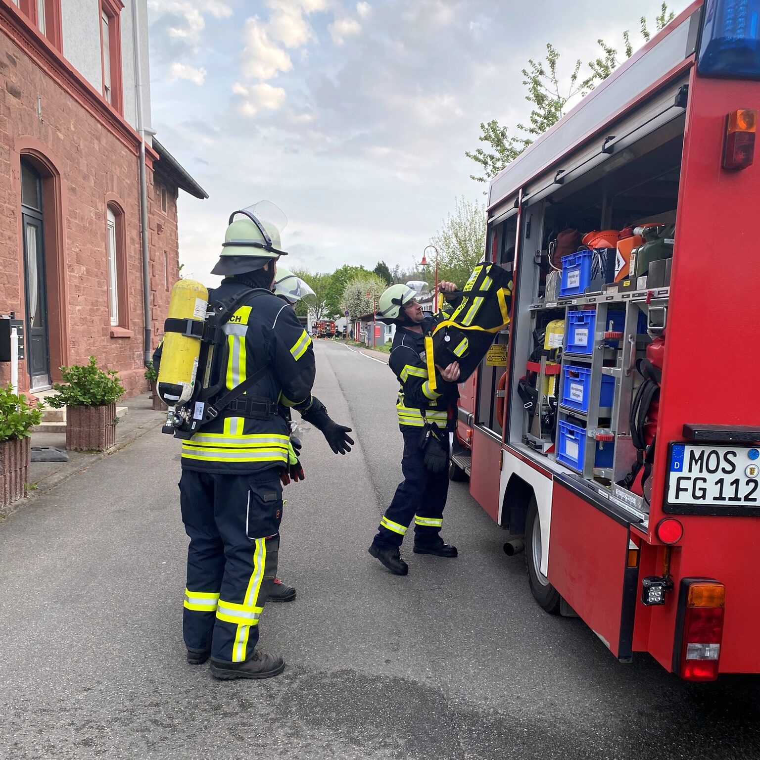 Ein Feuerwehrmann holt eine große Tasche aus einem Feuerwehrauto.