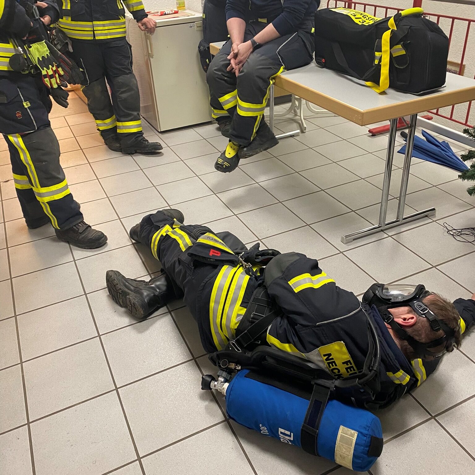 Ein Feuerwehrmann mit einer Flasche auf dem Rücken liegt auf dem Boden