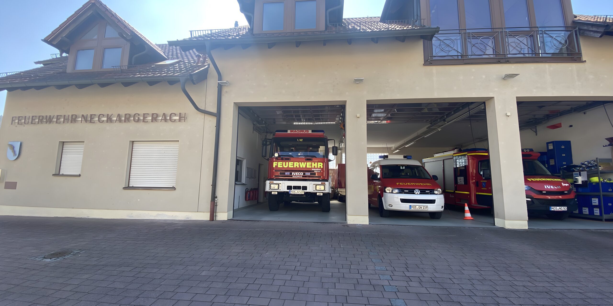 Das Gebäude der Feuerwehr. In drei Garagen stehen drei verschiedene Feuerwehrautos.